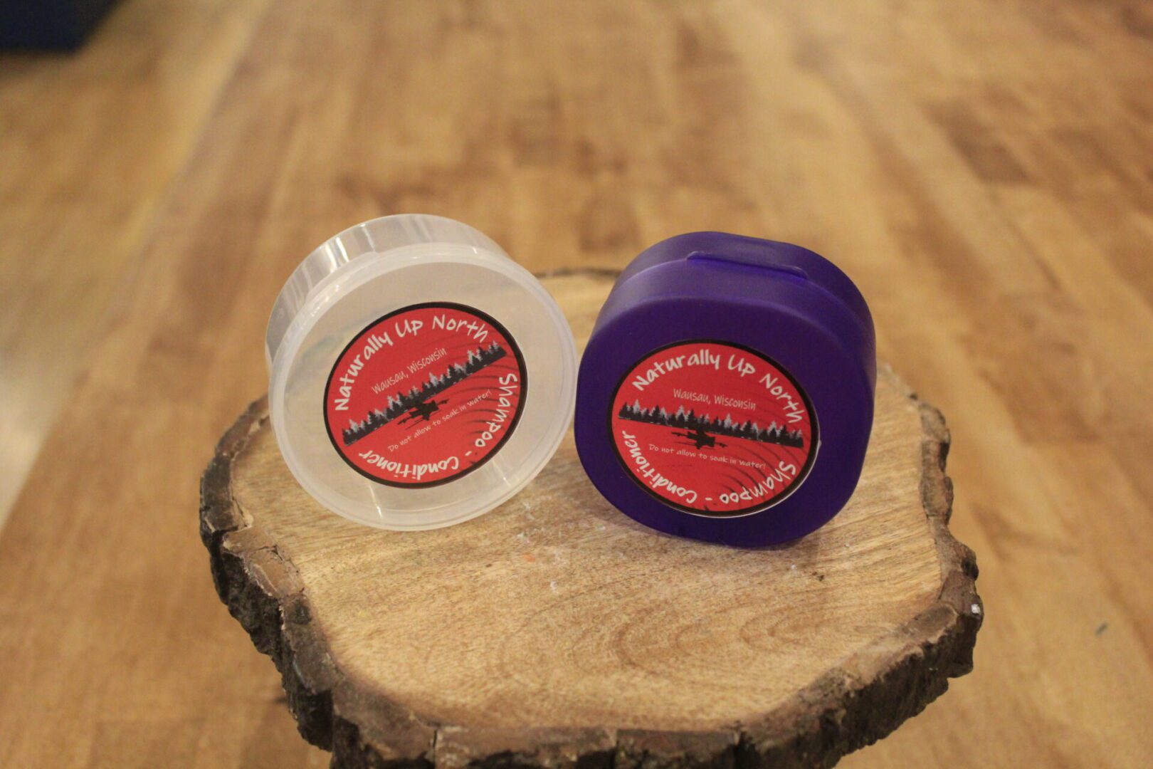 Two lip balm jars on wood slab